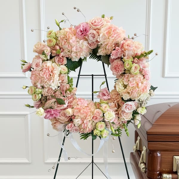 Pastel floral wreath on a stand with pink and cream blooms