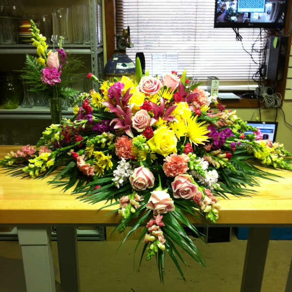 Large mixed floral arrangement with roses, lilies, and bright yellow blooms