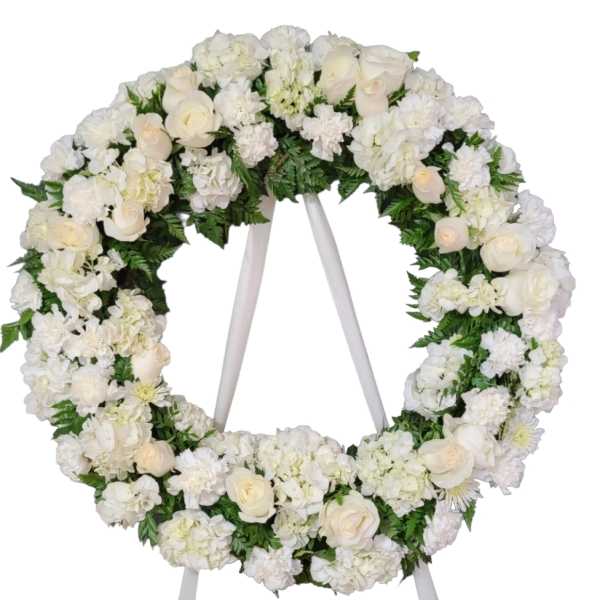 White floral wreath on a stand with roses and hydrangeas
