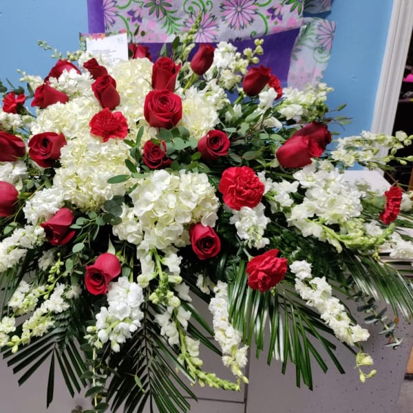 Large red rose and white floral arrangement with cascading greenery