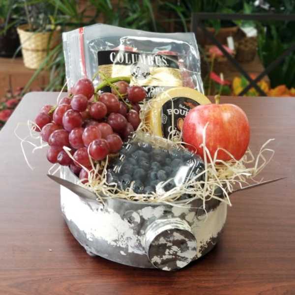 Fruit gift basket with grapes, an apple, and packaged snacks in a metal container
