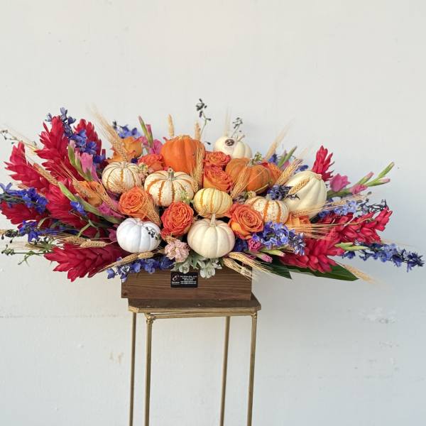 Autumn floral arrangement with pumpkins and orange roses in a wooden box