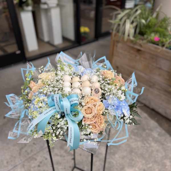 Bouquet of pastel roses and hydrangeas with decorative eggs and blue ribbon