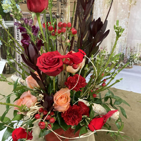 Tall floral arrangement with red and peach roses in a vase
