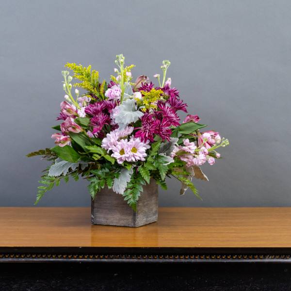 Mixed pink and purple flowers in a square vase on a table