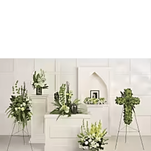 White floral funeral arrangements on stands and pedestals in a chapel setting