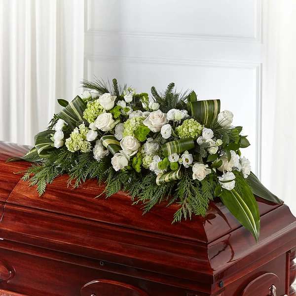 White and green floral spray on a polished casket