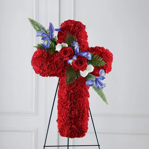 Red floral cross on a black stand with roses and blue flowers