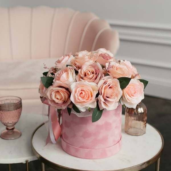 Pink rose arrangement in a round pink box on a table