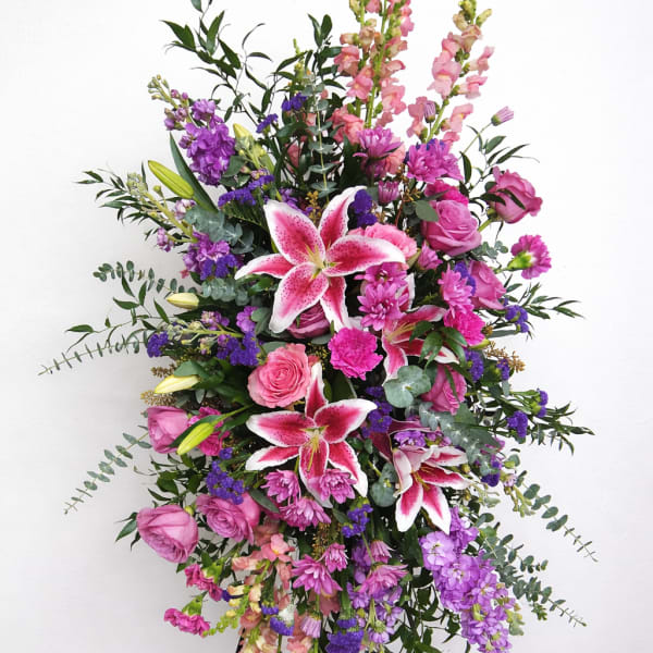 Tall standing floral spray with pink lilies and roses in pink and purple tones