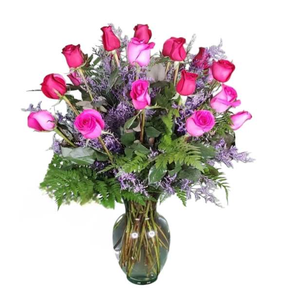 Pink roses arranged in a glass vase with purple filler flowers