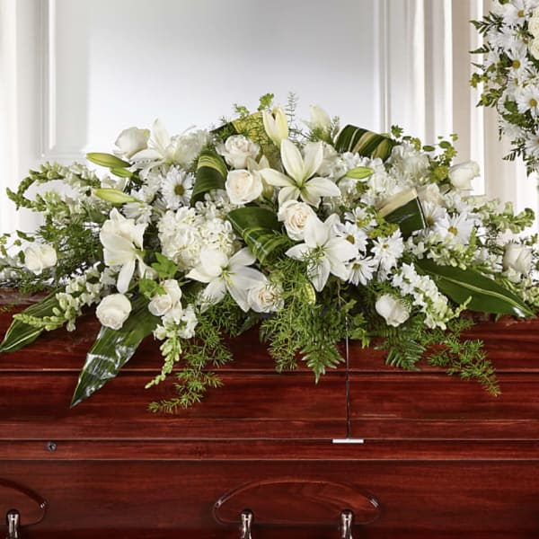 White floral casket spray with lilies, roses, and daisies