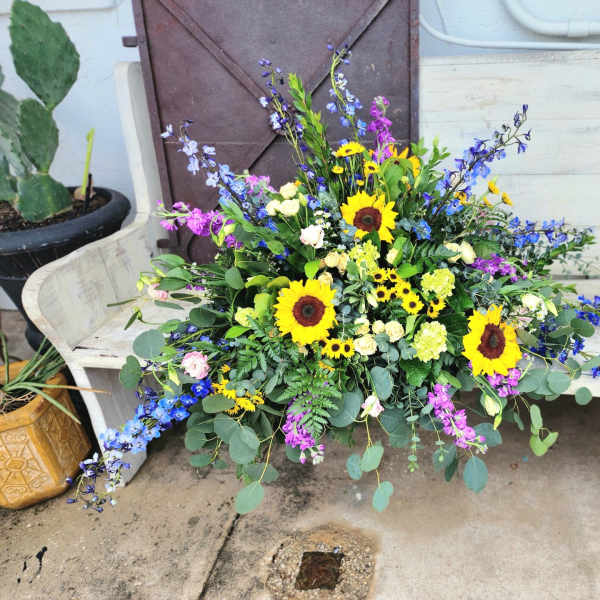 Large mixed bouquet with sunflowers and blue-purple flowers on a bench