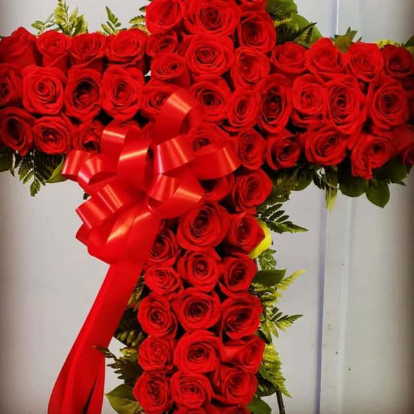 Cross-shaped arrangement of red roses with a red ribbon bow