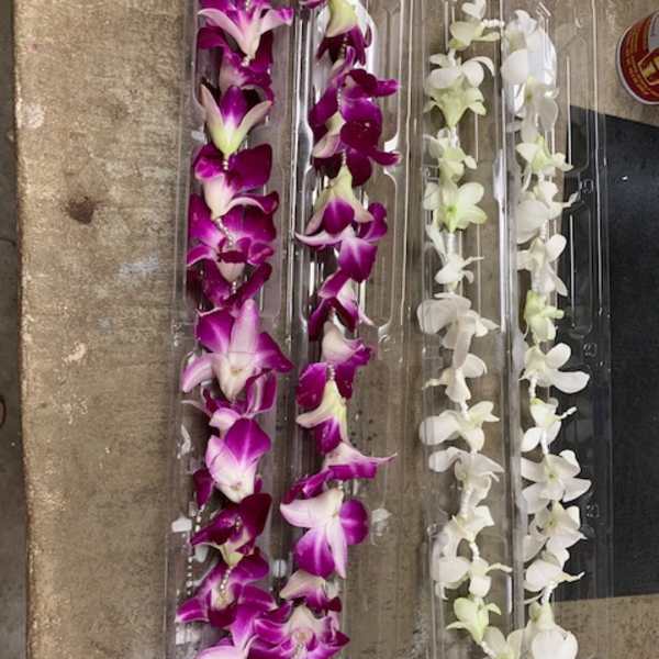 Clear plastic trays holding purple and white orchid garlands