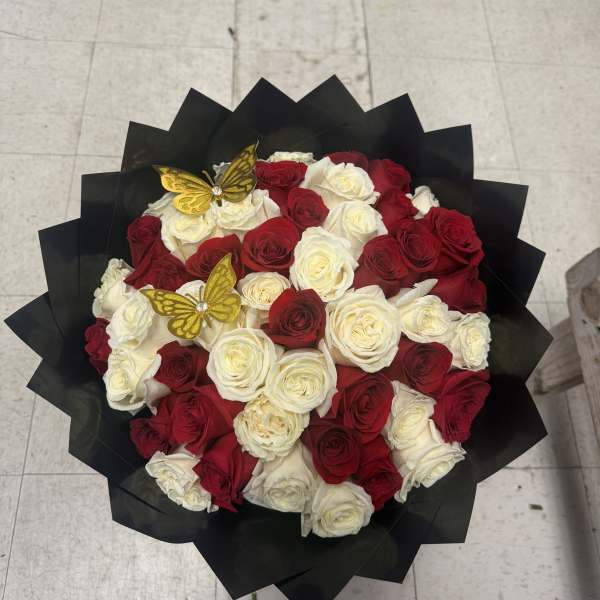 Bouquet of red and white roses wrapped in black paper with gold butterfly picks