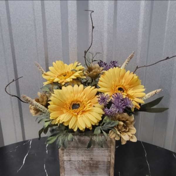 Yellow gerbera daisies in a rustic wooden box with purple accents