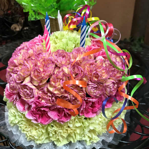 Round bouquet of pink and green carnations with ribbon curls and birthday candles