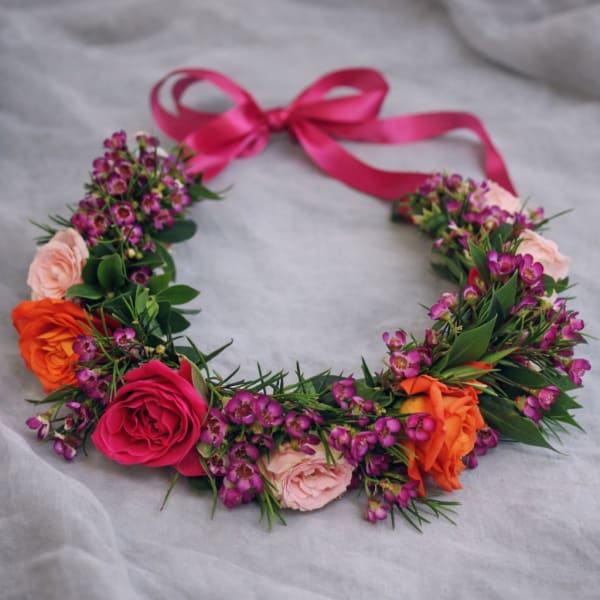 Floral crown with pink, orange, and purple flowers tied with a pink ribbon