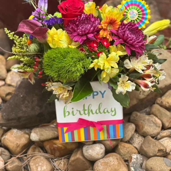 Colorful birthday flower arrangement in a gift bag with a ribbon
