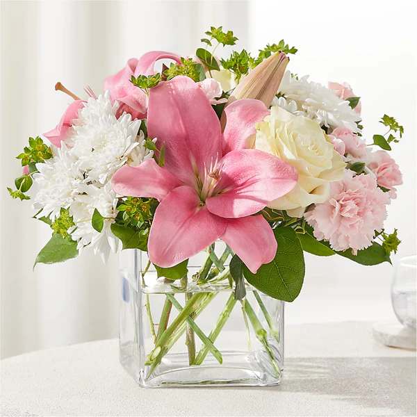 Pink lilies and white flowers in a clear glass vase