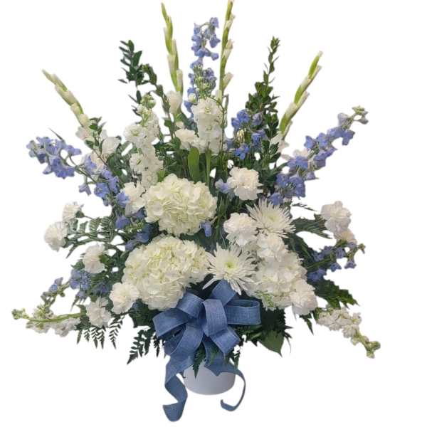 White and blue floral arrangement in a white container with a blue ribbon