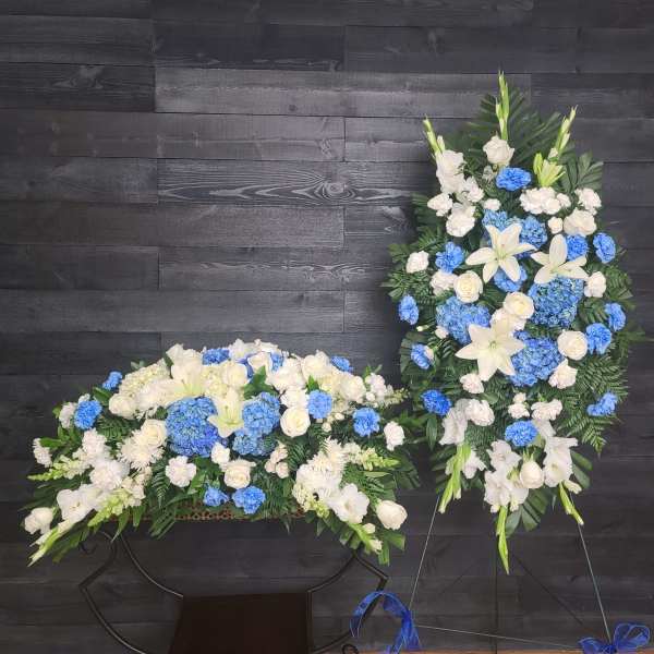 White and blue floral funeral sprays with lilies and roses on stands