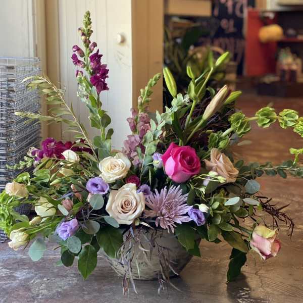 Mixed bouquet in a low vase with roses, lilies, and purple blooms