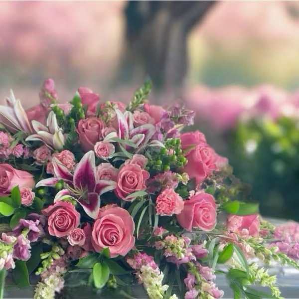 Pink rose and lily funeral spray on a casket