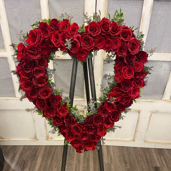 Heart-shaped red rose wreath on a black easel