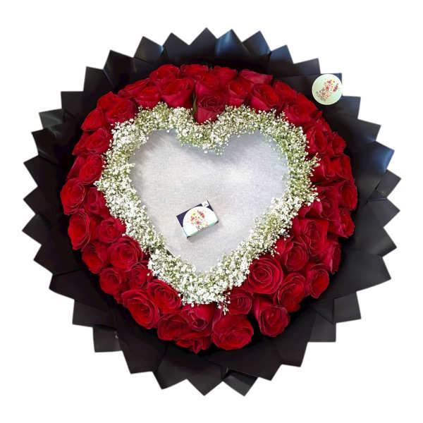 Heart-shaped arrangement of red roses with white baby's breath on black wrap
