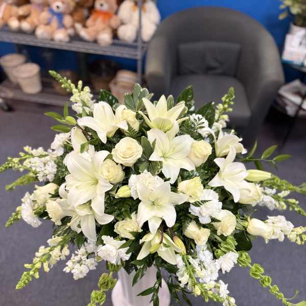 White lilies and roses arranged in a tall vase