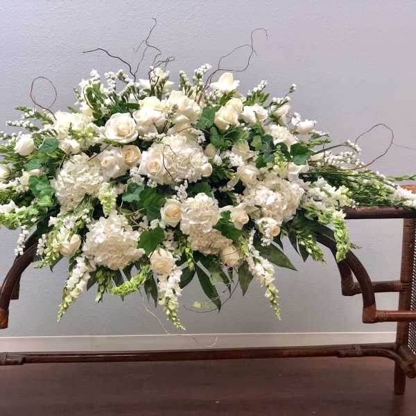 Large white floral arrangement with roses and hydrangeas on a wooden table