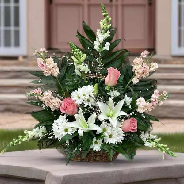 Basket arrangement of pink roses, white lilies, and daisies