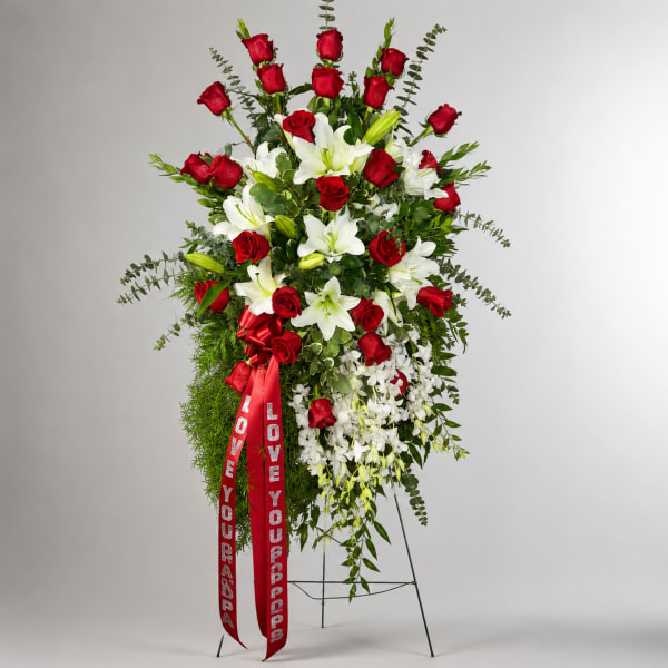Standing floral spray of red roses and white lilies with a red ribbon