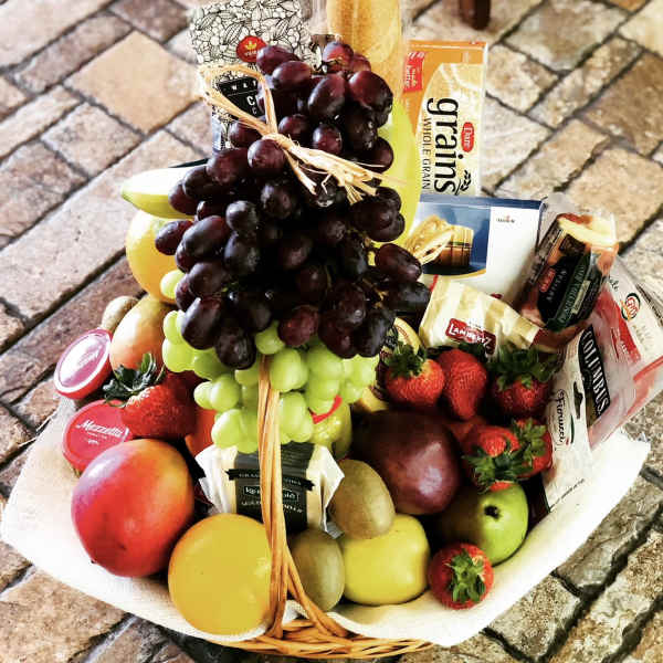 Fruit and snack basket with grapes, strawberries, apples, and packaged crackers