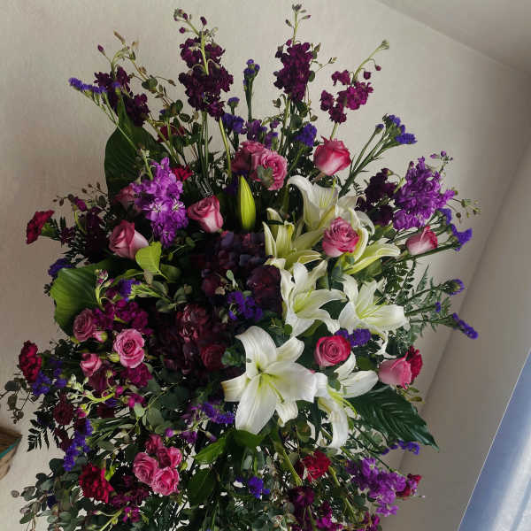 Large standing spray with white lilies, pink roses, and purple flowers