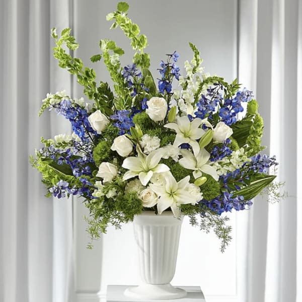 White lilies and roses with blue flowers in a white vase