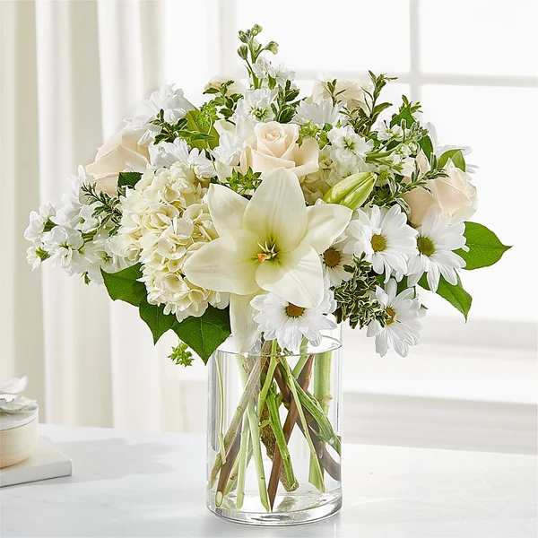 White flowers arranged in a clear glass vase with green accents