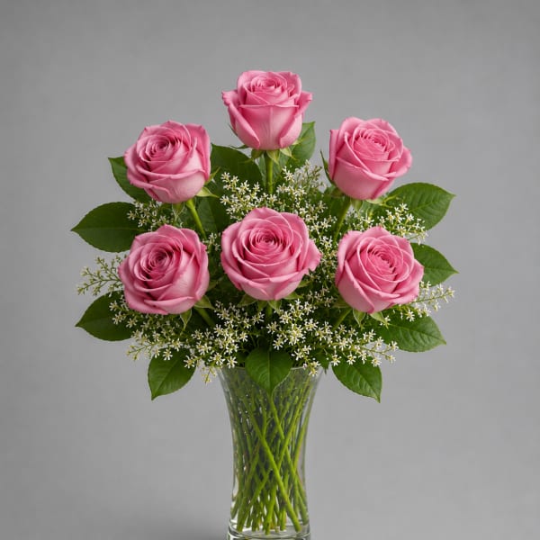 Pink roses arranged in a clear glass vase with small white filler flowers