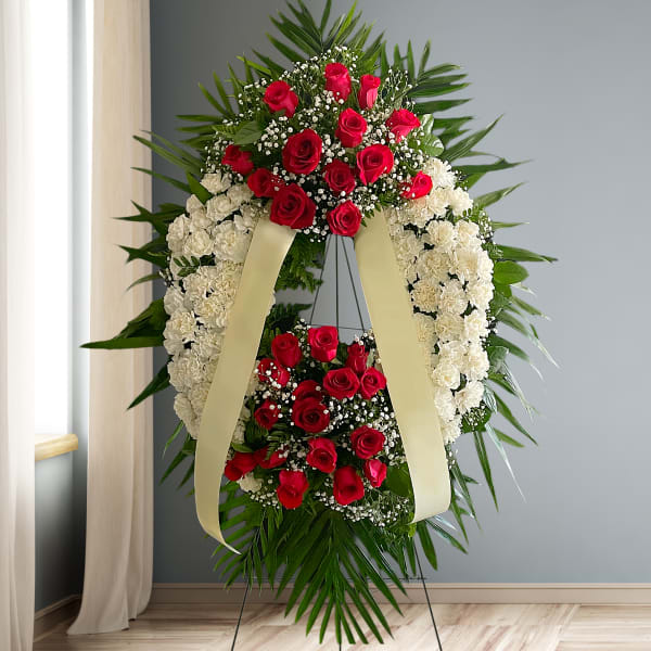 Standing funeral wreath of red roses and white carnations with cream ribbons