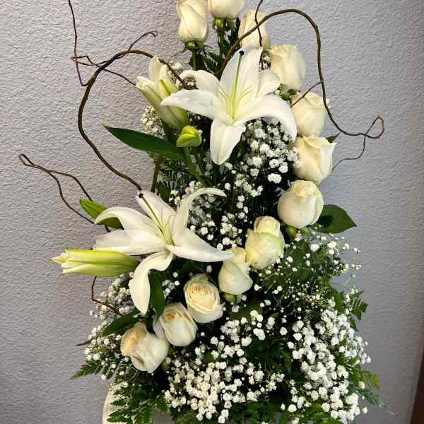 White lilies and cream roses in a white vase with baby's breath