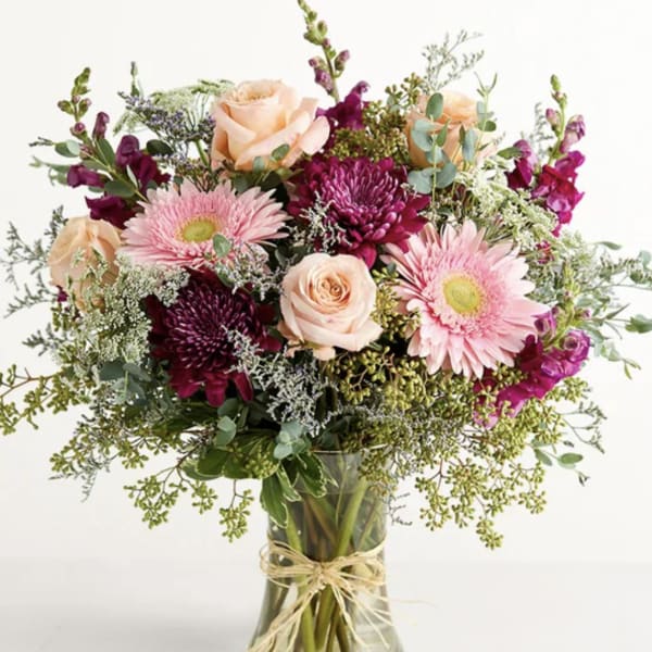 Mixed bouquet of pink and peach flowers in a clear glass vase