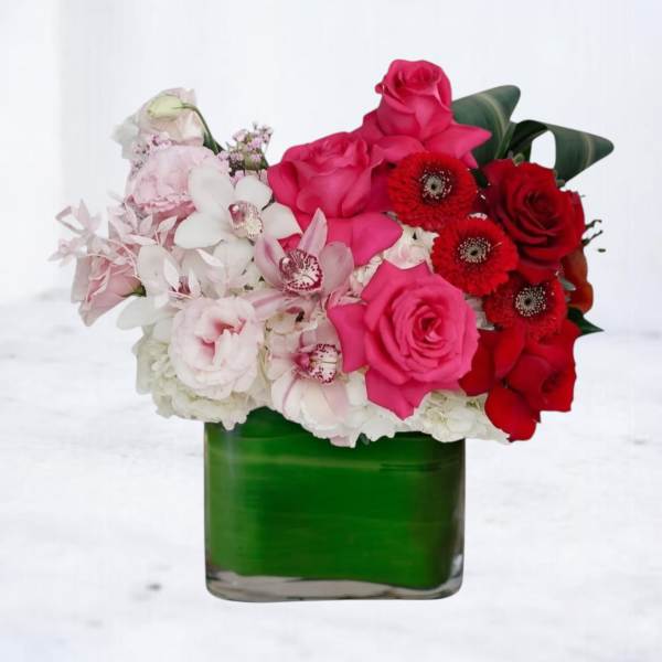 Pink and red flower arrangement in a green glass vase