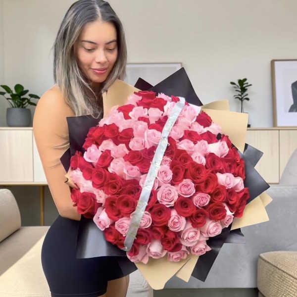 Large bouquet of red and pink roses wrapped in black and beige paper