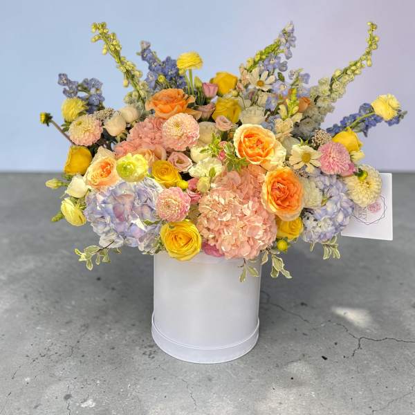 Mixed pastel bouquet in a white hatbox with roses and hydrangeas