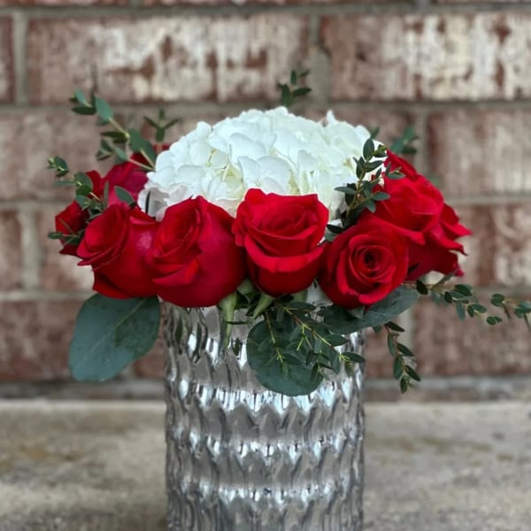 Red roses and white hydrangea in a clear glass vase