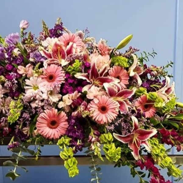Large pink and purple floral arrangement on a table beside a lantern