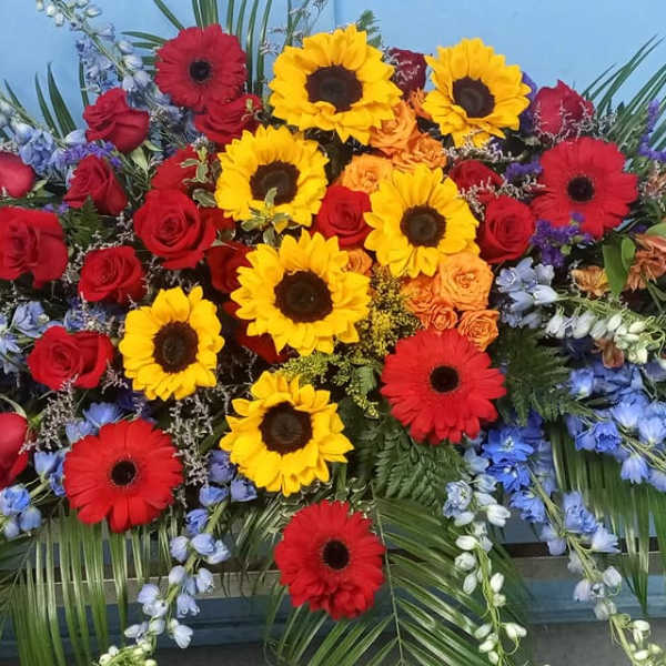 Large casket spray with red roses, yellow sunflowers, and red gerbera daisies