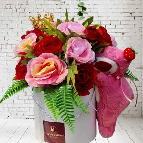 Pink and red rose arrangement in a white box with a pink teddy bear